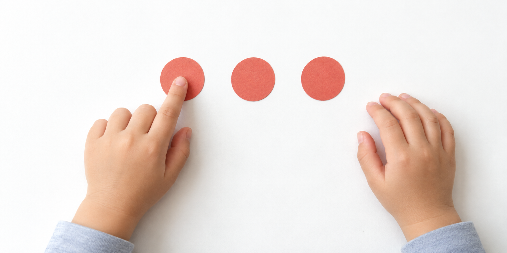 Child tapping three round markers in sequence on a white table