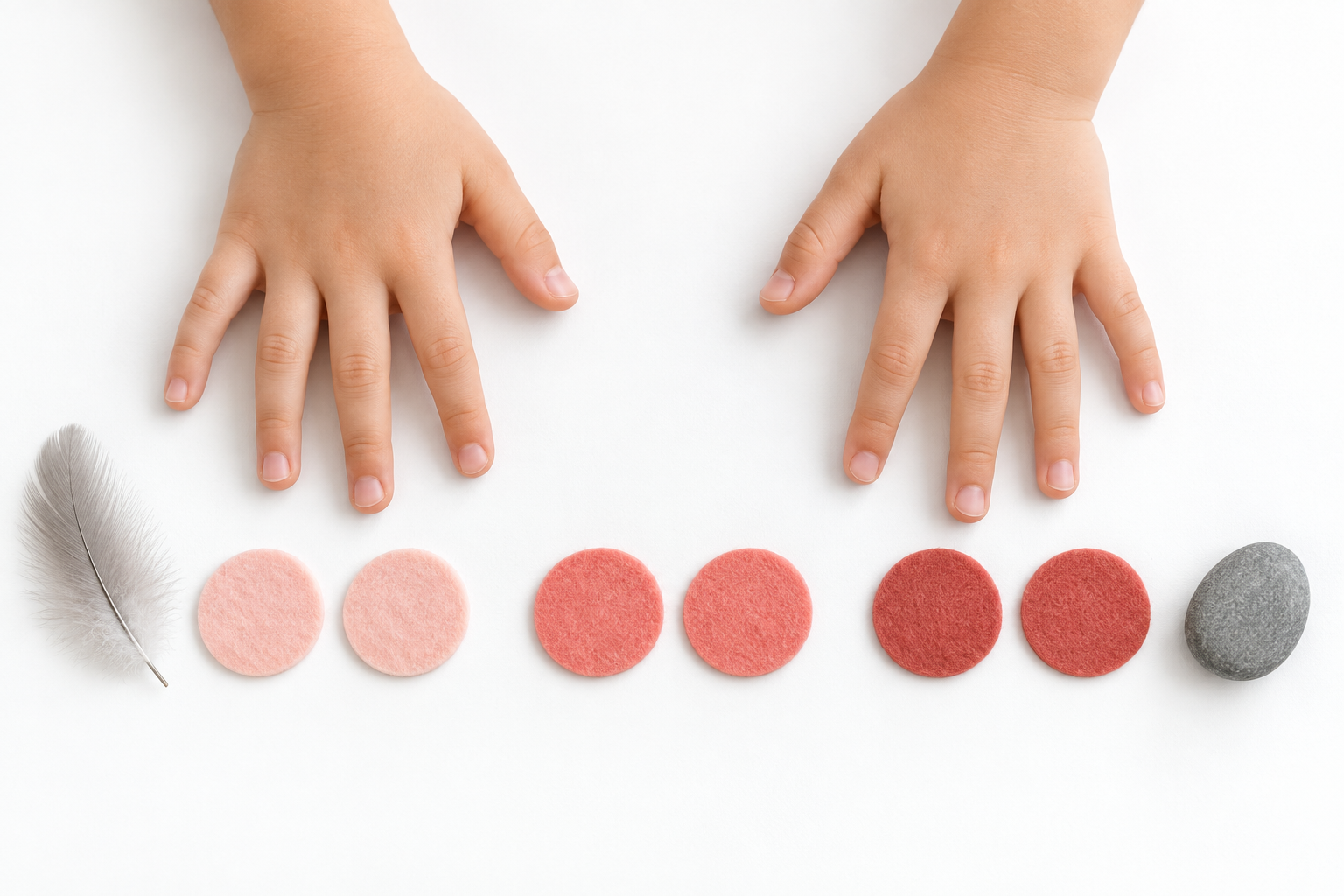 Child hands above three pairs of felt markers with a feather and smooth pebble