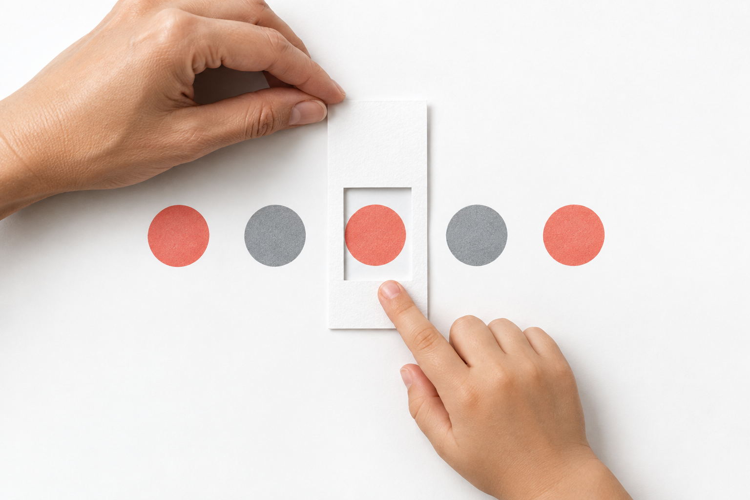 An adult and child use a simple index-card window to focus on one coral marker in a short row
